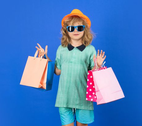 Fashion child on shopping. Portrait of a kid with shopping bags. Happy boy holding shopping bags. Studio portrait