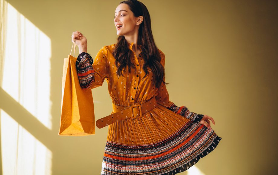 Young woman with shopping bags in a beautiful dress in studio